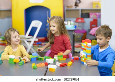 Three Happy Kids Playing With Plastic Building Blocks At Kindergarten