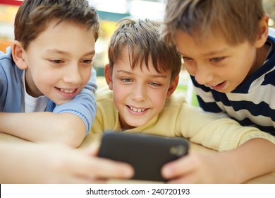 Three happy little boys using cellphone - Shutterstock ID 240720193