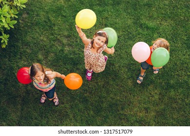 Three Happy Little Kids Playing With Colorful Balloons Outdoors, Top View