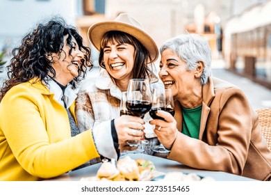 Three happy retired female drinking and toasting red wine glasses at bar restaurant - Group of happy elderly women having fun in the city - Concept about older friends smiling and laughing together - Powered by Shutterstock