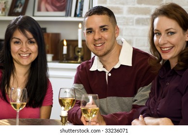 Three happy, smiling friends enjoying wine and each other's company.