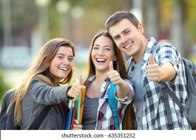 Three happy students looking at you with thumbs up in an university campus - Shutterstock ID 635351252