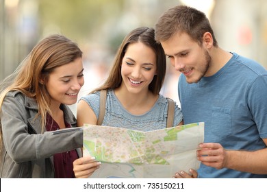 Three happy tourists consulting a paper map to find a location on the street