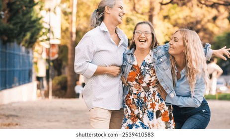 Three happy women laughing and smiling together outdoors, celebrating friendship and inclusion - Powered by Shutterstock