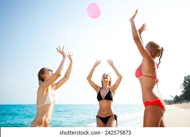 Three happy young girlfriends playing volleyball at the tropical beach, unfocused - Powered by Shutterstock