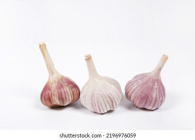 Three Heads Of Young Garlic On A White Background.The Concept Of Agriculture.Natural, Healthy, Environmentally Friendly Food For People.Cultivation Of Winter Varieties Of Garlic On The Plantation.