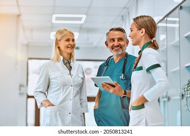 Three healthcare workers stand using tablet computer together in a hallway in the hospital. Low angle. Selective focus. - Powered by Shutterstock