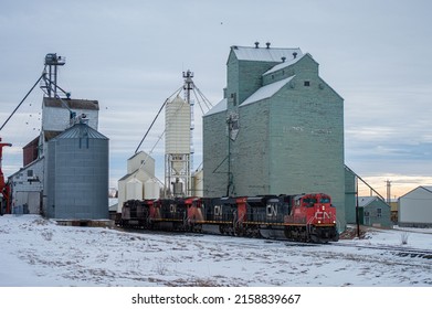 THREE HILS, CANADA - May 05, 2022: A freight train with grain elevators on the snowy railroad in Three Hills, Canada