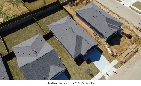 Three home alignment developing block at Highpointe Ranch, US 377, Blackjack Rd completed houses beside active yard and driveway work. Gray shingles, fresh lawns, raw soil textures, Aubrey, TX. USA
