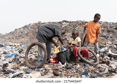 Three homeless street boys in a landfill with their daily loot of garbage to recycle and sell; condition of slum children in Africa