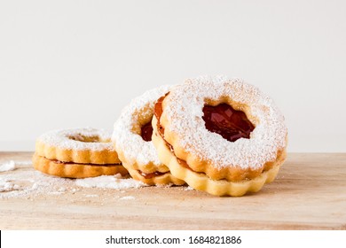 Three homemade linzer cookies are sitting on a cutting board.