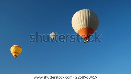 Three hot air balloons with tourists against a blue cloudless sky. Beautiful view of colourful hot air balloons from below
