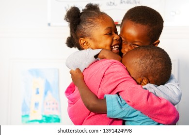 Three Hugging Close Black Kids In Nursery Class