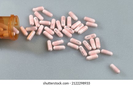 Three Hundred Milligram Pink Lithium Carbonate Capsules Spilling Out Of A Prescription Drug Container Onto A White Surface.