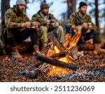 Three hunters in winter gear sit around a campfire in the forest, enjoying the warmth and hot drinks after a day of hunting