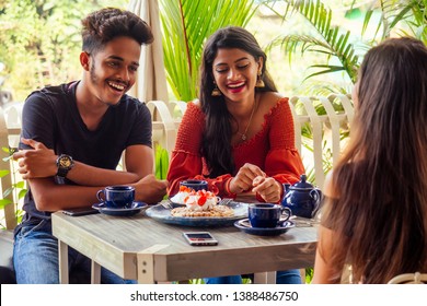 Three Indian Beat Friends Eating Sweets Pancakes With Masala Tea In Summer Tropical Beach Cafe