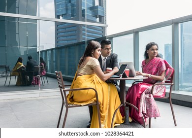 Three Indian business people with worried facial expression talking during break at work