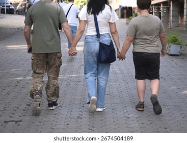 Three individuals hold hands while walking down a charming cobblestone street
