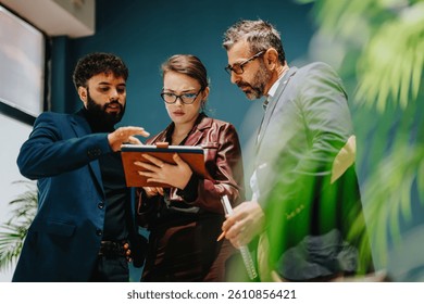 Three individuals in a modern business setting discussing and analyzing information from a document, showcasing teamwork, strategy, and professionalism within a corporate environment.