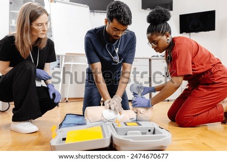 Three individuals practice CPR techniques on a training dummy in a classroom setting.