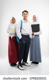 Three Indonesian teenagers wearing school uniforms smile at the camera with a backpack, a book, and a laptop computer with an isolated background - Shutterstock ID 1998205031