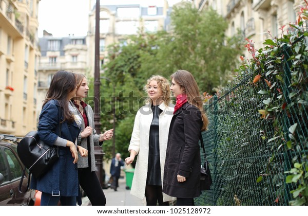 Three international students learning\
English and passing in  . Concept of language courses and preparing\
for lessons. Girls walking in city after\
classes.