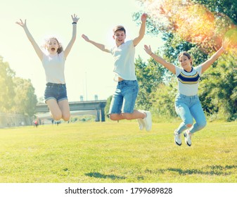 Three joyful teens jump on a spring lawn - Shutterstock ID 1799689828