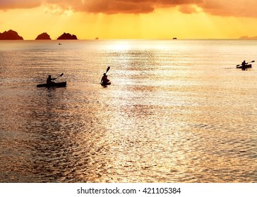 three kayak float at sunset