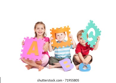 Three kids having fun learning with alphabet ABC letters. Isolated on white.