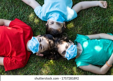 THree Kids Lying Down On A Grass With Safety Masks