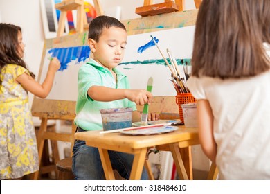 Three Kids Mixing Paint And Working On A Painting During Art Class At School