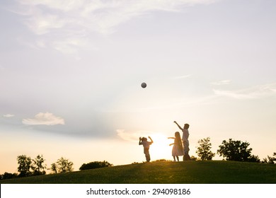 Three Kids Are Playing With A Ball On Sunset.