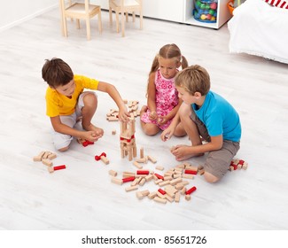 Three Kids Playing With Wooden Blocks In Their Room - Top View