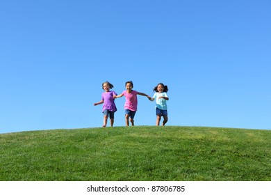 Three Kids Running On Grass Hill With Blue Sky