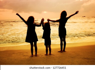 Three Kids Silhouettes Standing On Beach At Sunset