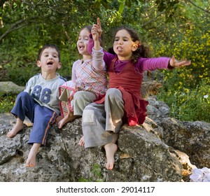 Three Kids Siting On A Rock Singing Outdoors