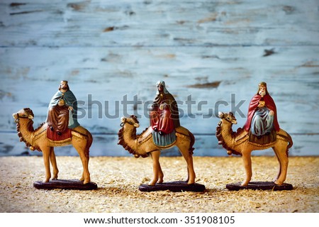 the three kings in their camels carrying their gifts for the Baby Jesus on a rustic nativity scene