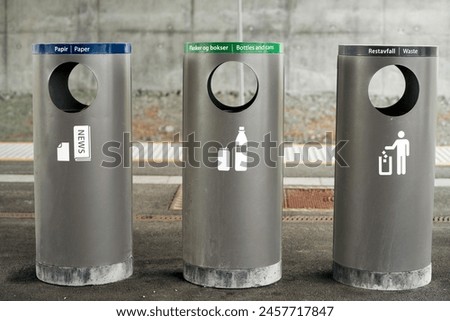 Three labeled recycling bins for paper, bottles, and waste, encouraging environmental responsibility. Modern recycling bins for waste separation
