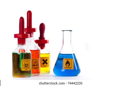 Three  laboratory dropper bottles and a conical flask with different coloured liquids and labelled with standard labels as toxic, corrosive, irritant and flammable.  On white.