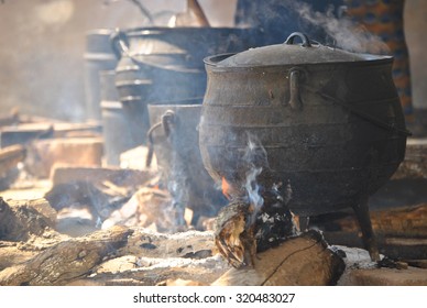 three large cooking pots on fires with smoke