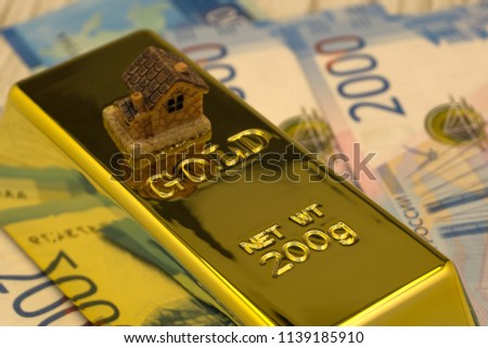 three large gold bars at many dollar bills