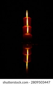 three large red candles stand on the ice and burn, reflecting