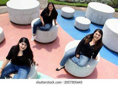 Three Latin Adult Sisters As A Loving Family Happily Dressed In Black Outdoors In A Park In Harmony, Freedom And Happiness
