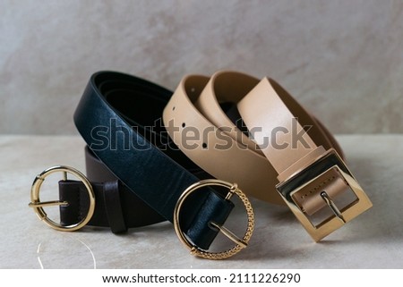 Three leather belts of different shades rolled together