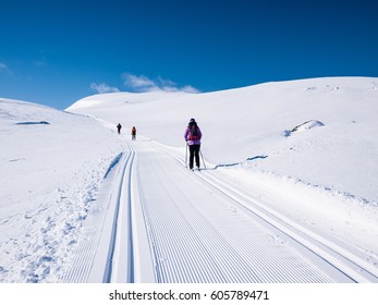 Three leisure cross-country skiers in a well prepared double groomed track in the norwegian mountains at easter going up hill