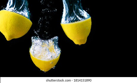 Three lemon halves falling into water with air bubbles on black background