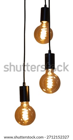 Three light bulbs hang down from black cords. The bulbs are lit and give off a warm glow. They are positioned individually but close together against a white surface.