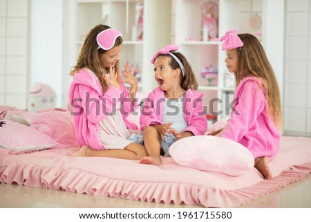 Three little girl sitting on bed. Little girl showing her nails. 