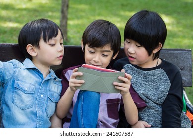 Three Little Handsome Boy Looking On Ipad Tablet And Playing Game At Park