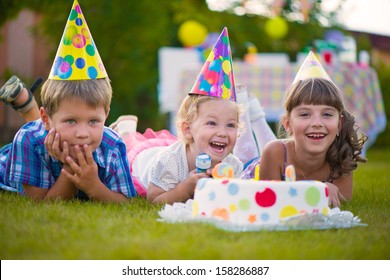 Three Little Kids Celebrating Birthday On Green Grass